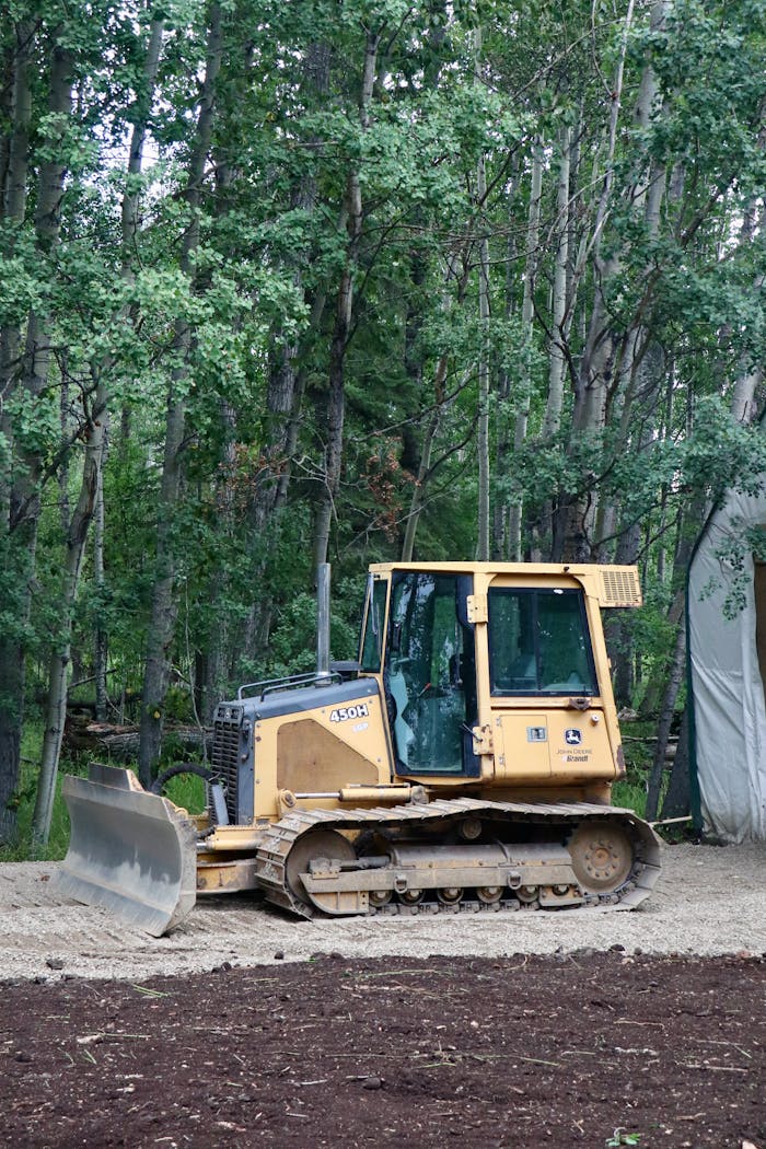 services-10 Yellow bulldozer in forest clearing preparing soil for landscaping project.