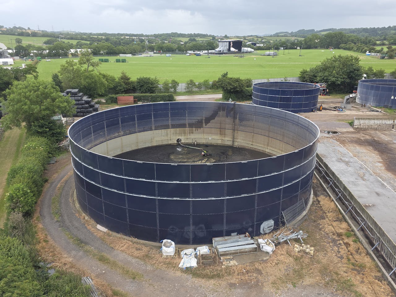 gallery-06 Aerial photo showcasing large industrial water tanks amidst lush countryside landscape under cloudy sky.